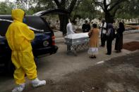 Family members surround the coffin containing the body of a woman who died of the coronavirus disease (COVID-19) at the San Rafael cemetery in Mexico City