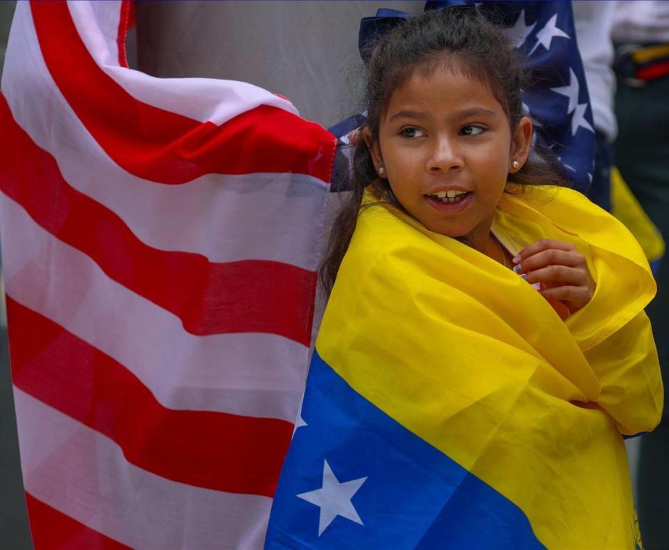 Catalina Belén, de 8 años, mira con entusiasmo mientras se envuelve en la bandera venezolana mientras asiste a la manifestación por el derecho a votar en las elecciones venezolanas con sus padres, en la antigua sede del consulado de Venezuela en Miami, el domingo 28 de julio de 2024 en Miami, Florida.