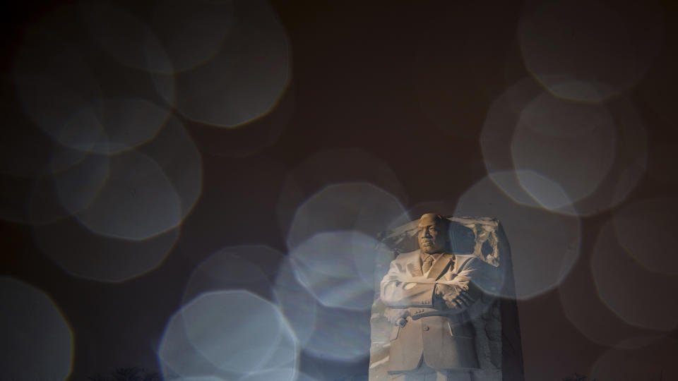 In a long exposure photo, lights from a snowplow illuminate sleet at the Martin Luther King Jr. Memorial in Washington, Sunday, Jan. 16, 2022. Ceremonies scheduled for the site on Monday, to mark the Martin Luther King Jr. national holiday, have been canceled because of the weather. (AP Photo/Carolyn Kaster)