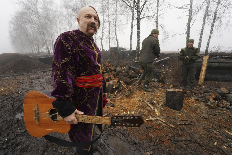 An artist dressed as a Cossack holds his guitar after performance for Ukraine's National Guard soldiers to mark Christmas at their position close to the Russian border near Kharkiv, Ukraine, Saturday Dec. 24, 2022. (AP Photo/Andrii Marienko)
