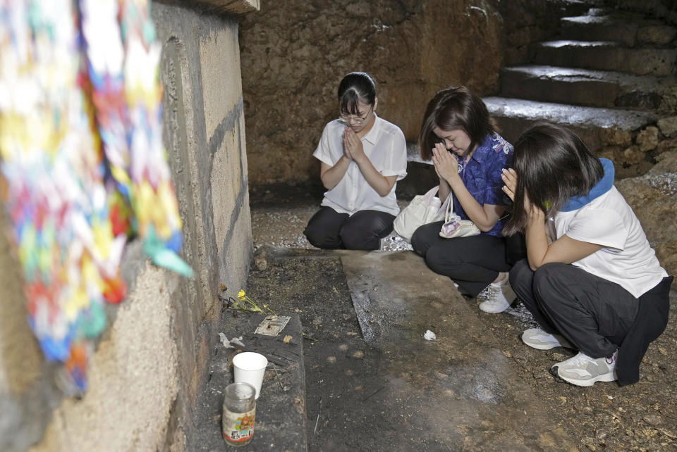 People pray for victims inside a cave at the Peace Memorial Park in Itoman, Okinawa prefecture, southern Japan Friday, June 23, 2023. Japan marked the Battle of Okinawa, one of the bloodiest battles of World War II fought on the southern Japanese island, which ended 78 years ago. (Kyodo News via AP)