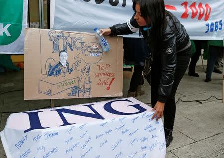 A demonstrator places a sign showing ING's chief executive near a coffin draped in ING's logo during a protest against job cuts in front of ING's main office in Brussels, Belgium, October 7, 2016. REUTERS/Francois Lenoir
