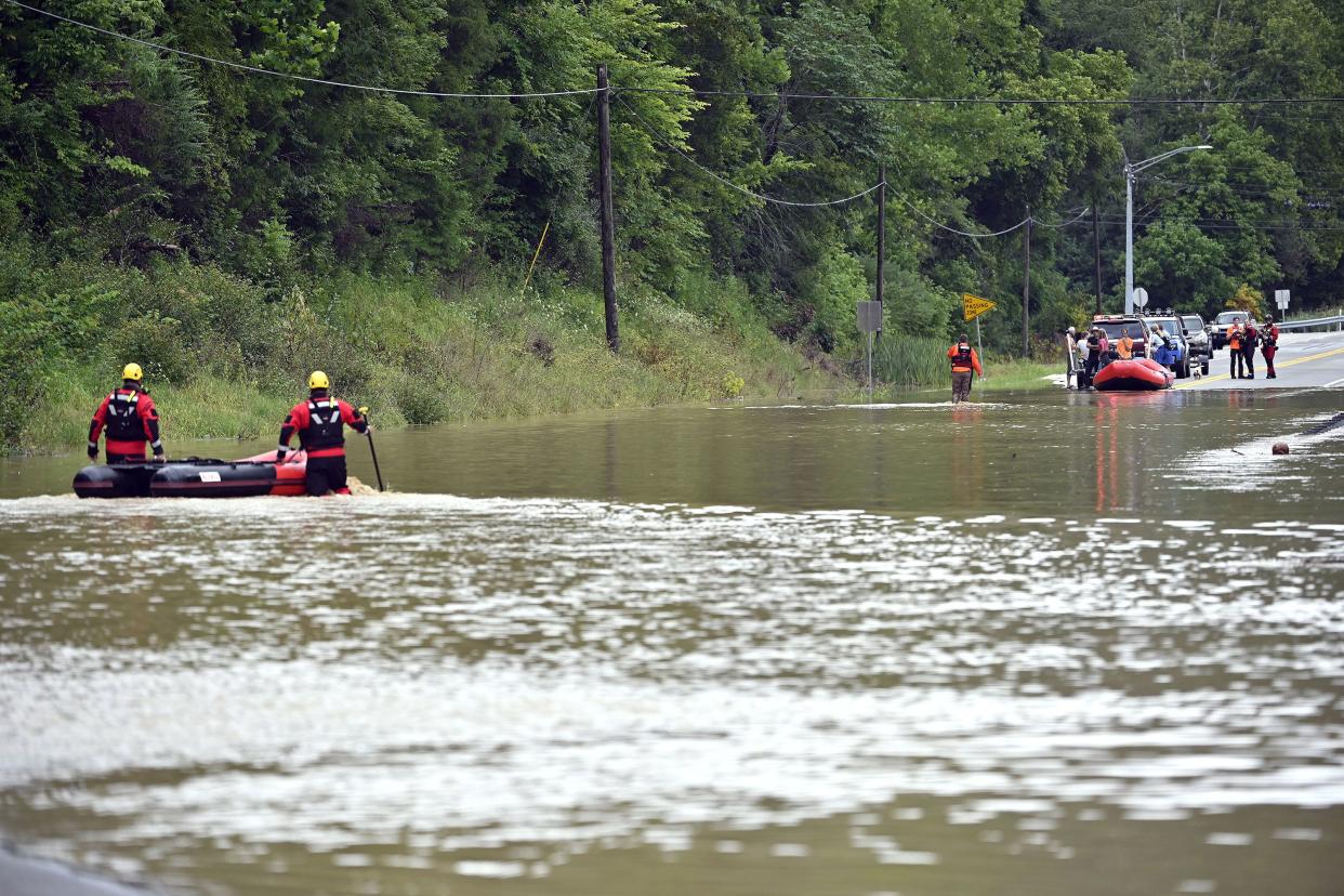 Members of the Winchester, Ky. Fire Department walk inflatable boats across flood waters over Ky. State Road 15 in Jackson, Ky. to pick up people stranded by the floodwaters on Thursday, July 28, 2022.