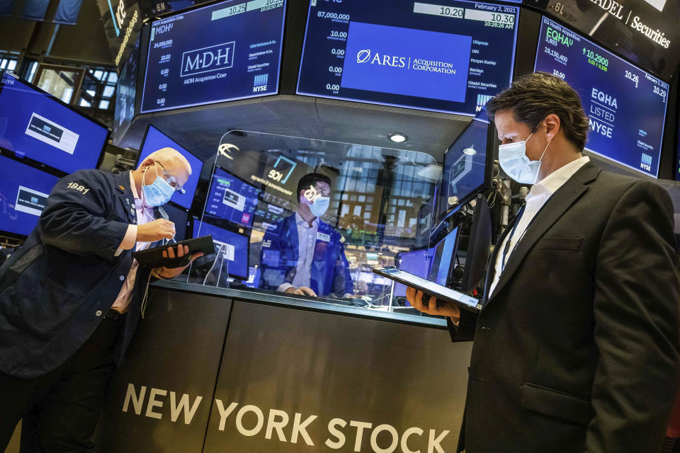In this photo provided by the New York Stock Exchange, specialist Thomas McArdle, center, works with traders on the floor, Tuesday Feb. 2, 2021. Stocks were broadly higher in afternoon trading Tuesday, but shares of closely watched companies like GameStop and AMC Entertainment were falling sharply. (Colin Ziemer/New York Stock Exchange via AP)