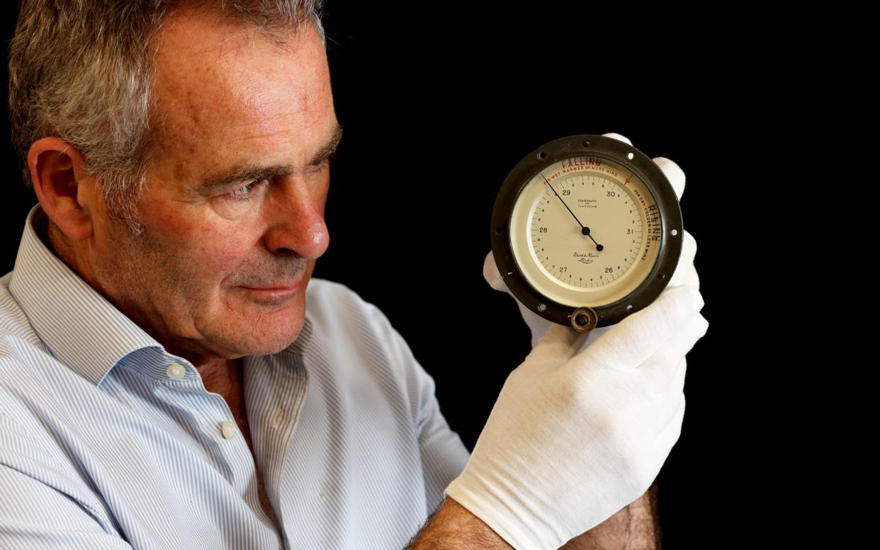 An auction house employee holds up the barometer, wearing white gloves