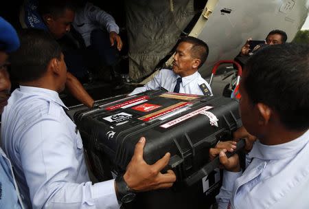 An Indonesian Air Force flight crew lift a case containing the flight data recorder from AirAsia QZ8501 onto a military plane for transport back to Jakarta at the airbase in Pangkalan Bun, Central Kalimantan January 12, 2015. REUTERS/Darren Whiteside