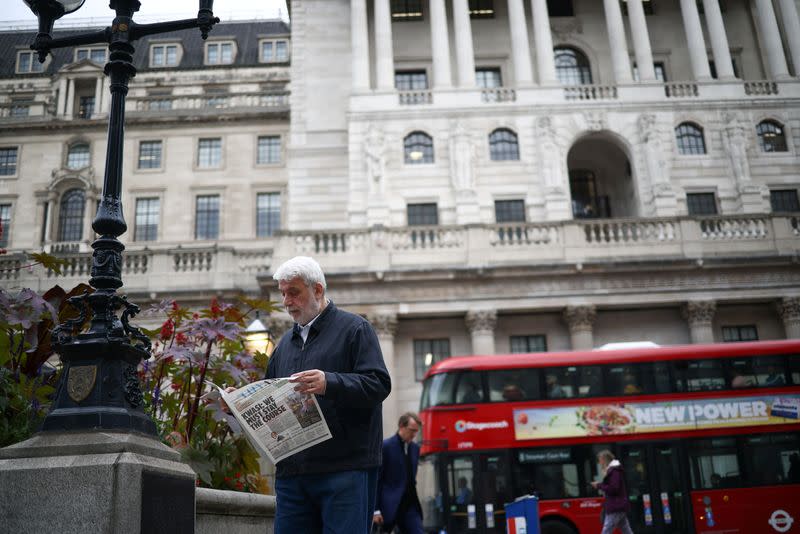 FILE PHOTO: A person reads a newspaper outside the Bank of England in the City of London financial district in London