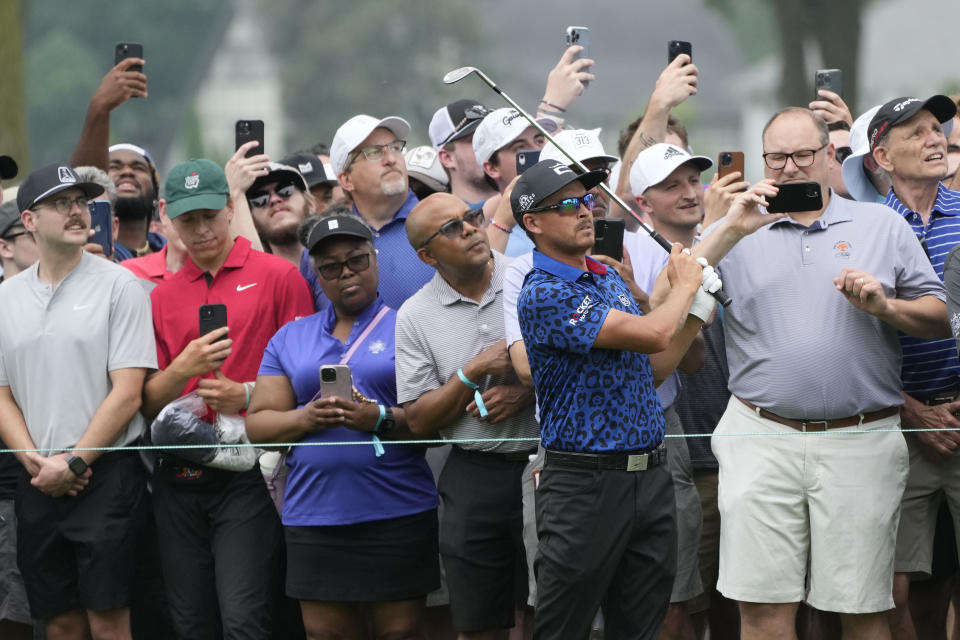 Spectators watch as Rickie Fowler hits onto the first green during the third round of the Rocket Mortgage Classic golf tournament at Detroit Country Club, Saturday, July 1, 2023, in Detroit. (AP Photo/Carlos Osorio)
