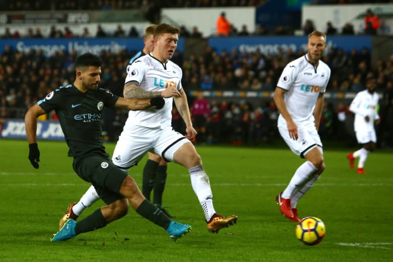 Manchester City's Sergio Aguero (L) has a shot on goal during their match against Swansea City in Swansea, south Wales on December 13, 2017