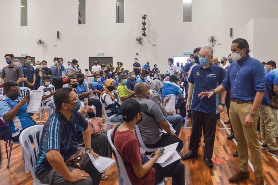 Khairy Jamaluddin (right) and Datuk Seri Wee Ka Siong greet members of the public during a visit to the vaccination centre at the Port Klang Sport Club’s multipurpose hall June 25, 2021. — Picture by Miera Zulyana