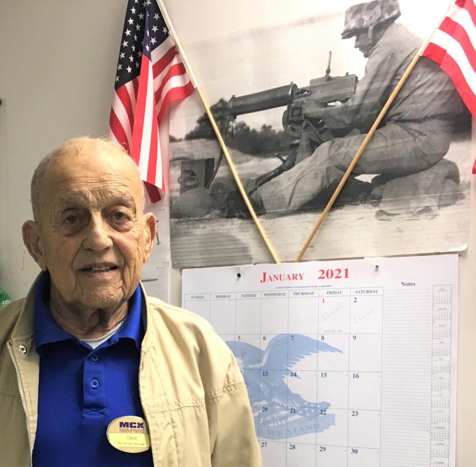 Retired U.S. Marine Corps Sgt. Maj. Marion "Cass" Carcirieri poses for a photo at his office on Camp Geiger in December 2020 while standing next to a picture of himself with his weapon of choice, a .30 caliber water-cooled machine gun, circa 1955.