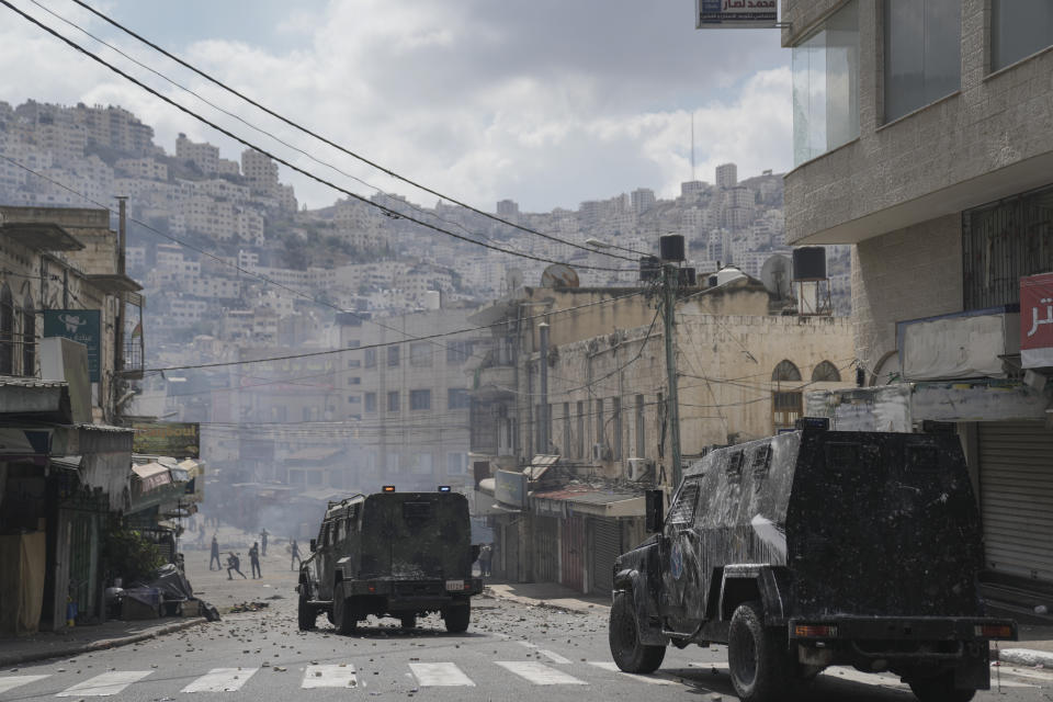 Palestinians clash with Palestinian security forces following an arrest raid against local militants, in the West Bank city of Nablus Tuesday, Sept. 20, 2022. Palestinian security forces on Tuesday exchanged fire with militants in the center of the West Bank's second-largest city, as angry residents pelted an armored jeep with objects and chased it away. One man was reported dead. The incident marked a rare case of deadly internal Palestinian fighting in the occupied West Bank. (AP Photo/Nasser Nasser)