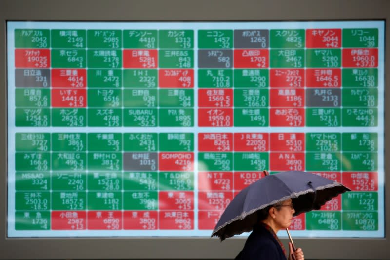 FILE PHOTO: A passerby walks past in front of a stock quotation board outside a brokerage in Tokyo, Japan, May 10, 2019. REUTERS/Issei Kato