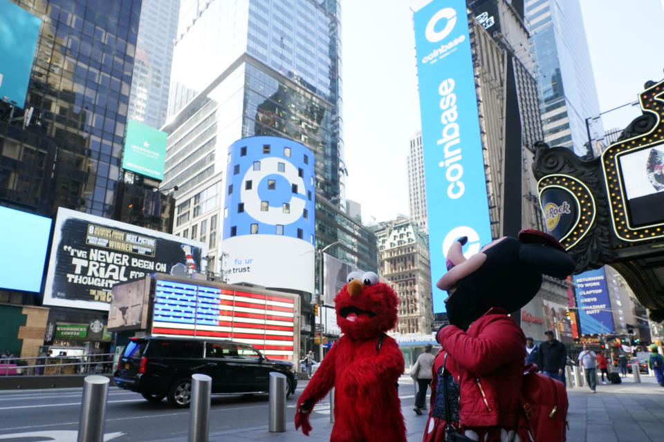 Costumed characters pass the Nasdaq MarketSite during the Coinbase IPO, in New York's Times Square, Wednesday, April 14, 2021. Wall Street will be focused on Coinbase Wednesday with the digital currency exchange becoming a publicly traded company. (AP Photo/Richard Drew)