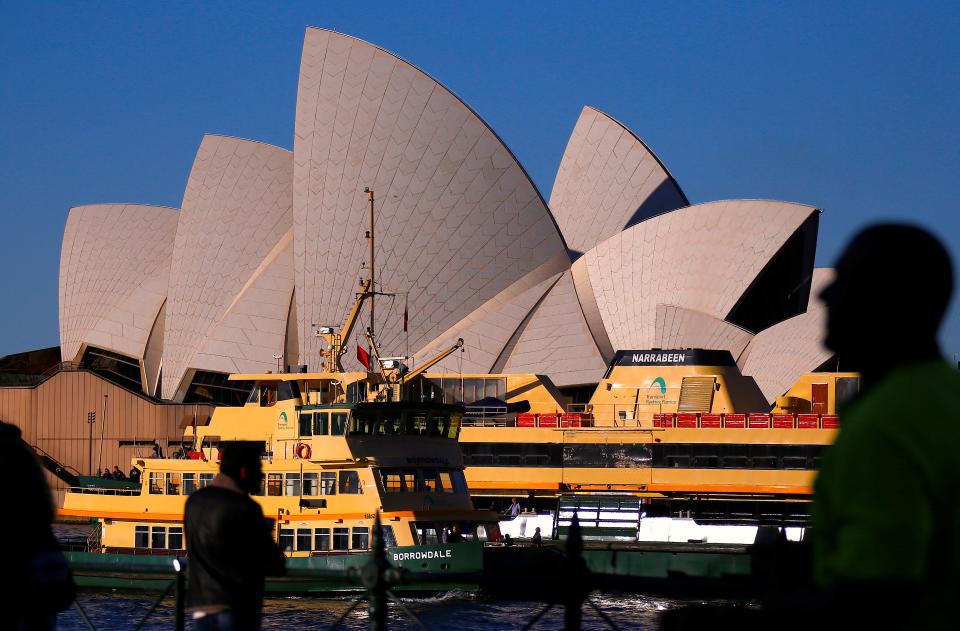 Pedestrians and passengers aboarding ferries can be seen in front of the Sydney Opera House in central Sydney, Australia July 30, 2018.   REUTERS/David Gray