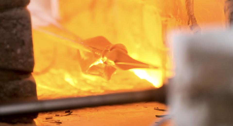 Molten glass is pulled into a thin string in the furnace