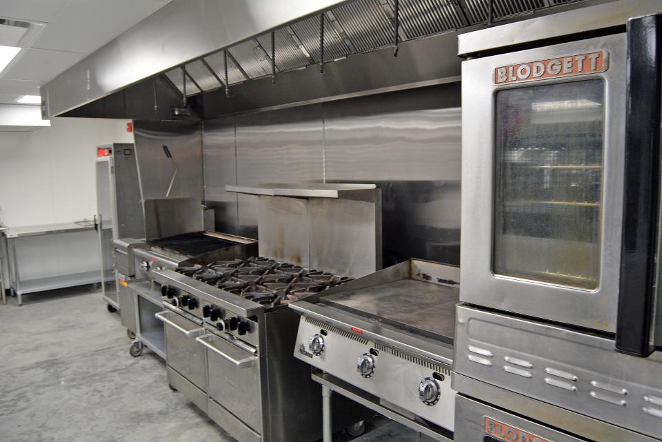 A view of the CoMoCooks kitchens hot production line featuring hot food storage, deep fryer, grated grill, commerical eight-burner range with two ovens, flat top grill and commercial double oven. 