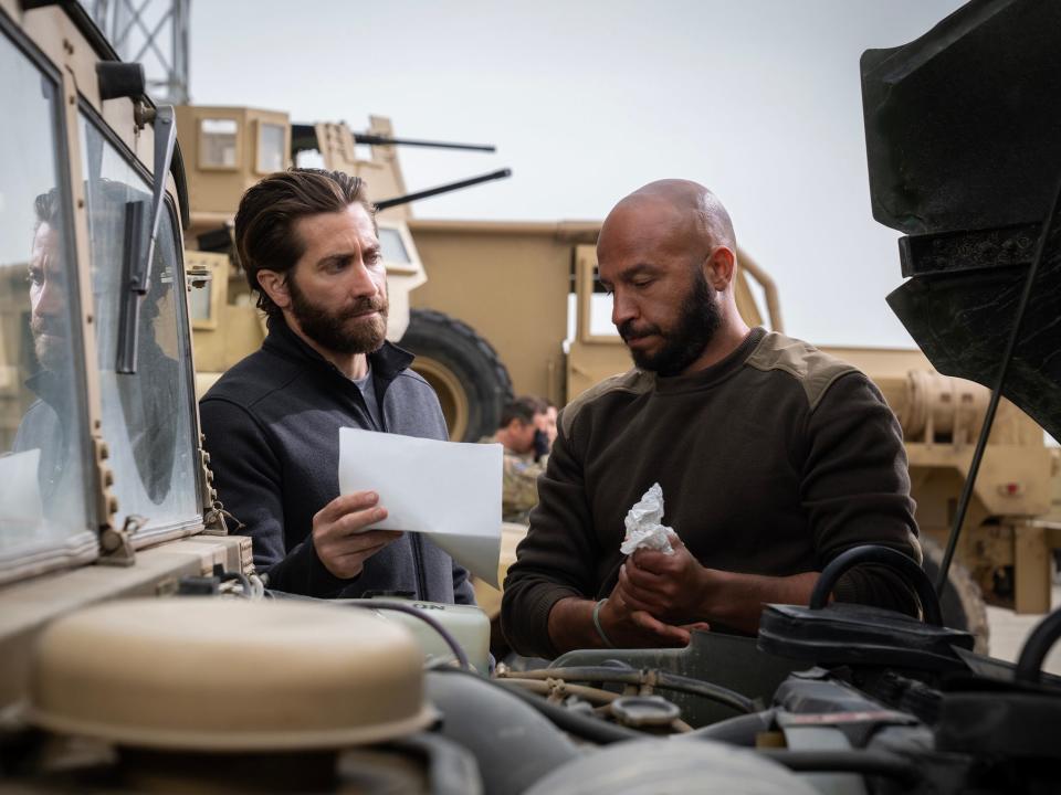 Jake Gyllenhaal showing Dar Salim a piece of paper as Salim works on a truck