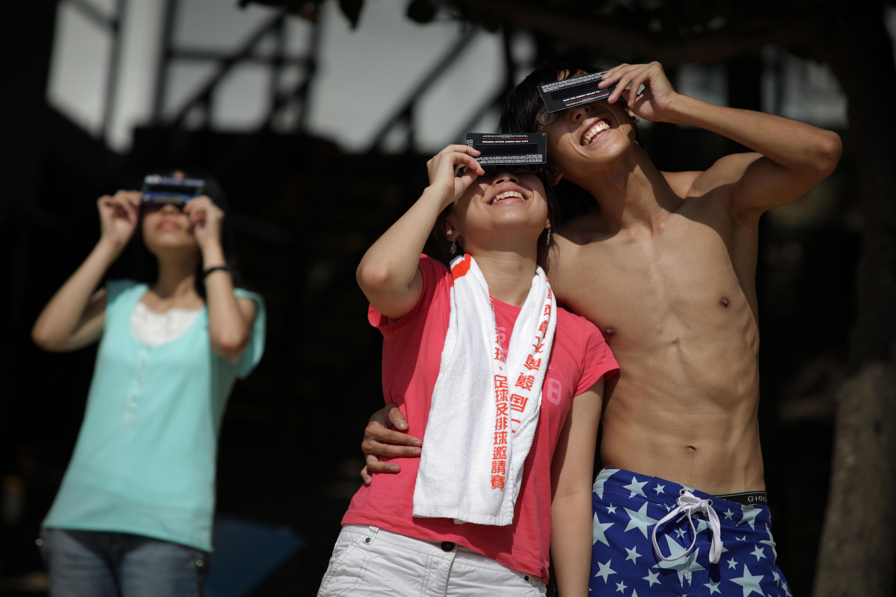 2009: People use special filters to view a partial solar eclipse setting over a beach in Hong Kong. 