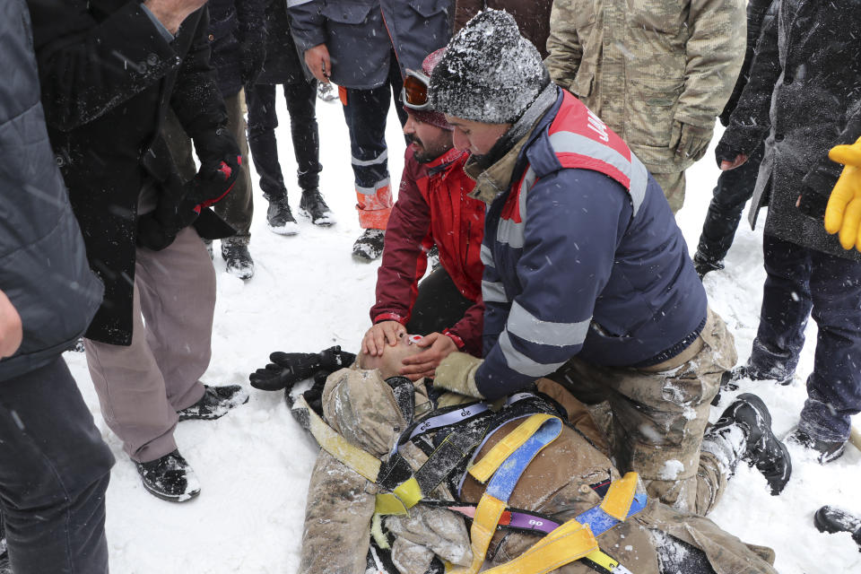 Emergency service members give first aid to victim of an avalanche, near the town of Bahcesaray, in Van province, eastern Turkey, Wednesday, Feb. 5, 2020. An avalanche slammed into a mountain road in the province, which borders Iran, wiping out a huge team of rescue workers sent to find two people missing in an earlier avalanche. (Feyat Erdemir/DHA via AP)