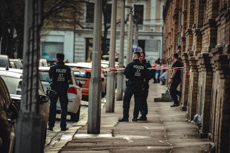 Police stand in front of a residential building in Halle, an area is cordoned off with tape. The police have found an object in an apartment in Halle which, according to initial investigations, is a detonable explosive device. Tom Musche/dpa-Zentralbild/dpa