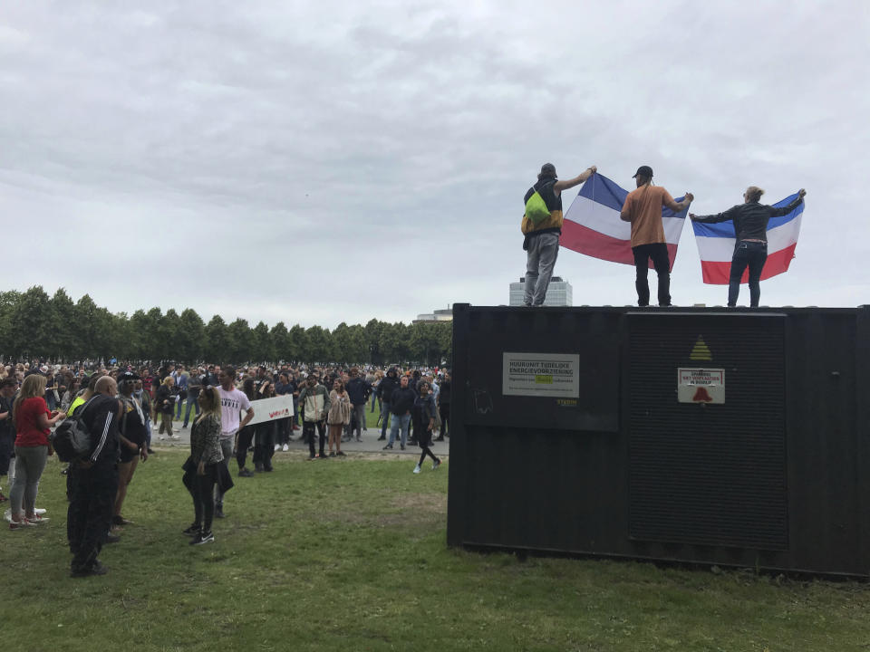 People hold up Netherlands flags as they stand on a power unit, during a demonstration targeting the government’s handling of the coronavirus crisis, at Malieveld, the Hague, Netherlands, Sunday, June 21, 2020. Dutch police charged hundreds of what they called soccer fans with horses and a water cannon in the center of The Hague Sunday and warned people to stay away from the city center. (AP Photo/Michael Corder)