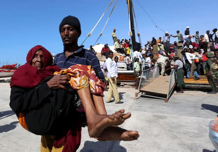 A man carries an elderly woman from a ship that has arrived, carrying people fleeing violence in Yemen, at the port of Bosasso in Somalia's Puntland region, April 16, 2015. REUTERS/Feisal Omar