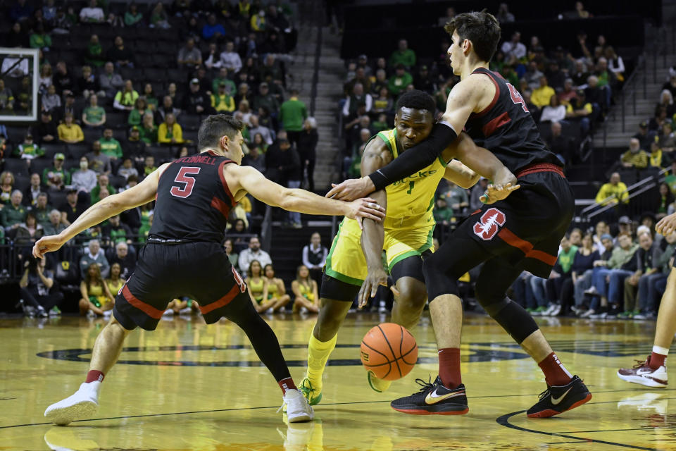 Oregon center N'Faly Dante (1) fights through defensive pressure by Stanford guard Michael O'Connell (5) and forward Maxime Raynaud, right, as he drives to the basket during the first half of an NCAA college basketball game Saturday, March 4, 2023, in Eugene, Ore. (AP Photo/Andy Nelson)
