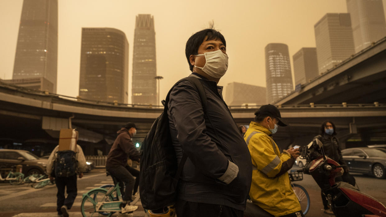 A commuter wears a protective mask while standing and waiting at a traffic light during a seasonal sandstorm on April 15 in Beijing.