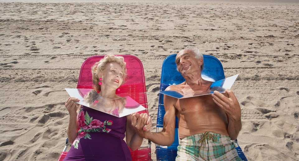 An older couple at the beach tanning themselves. 