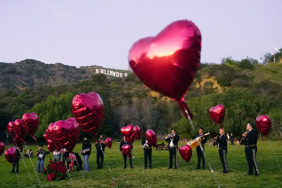 ARCHIVO - Una banda mariachi mexicana rodeada por globos en forma de corazón aguarda el arribo de una pareja para la fiesta de compromiso en Lake Hollywood Park, Los Ángeles, 14 de febrero de 2022. (AP Foto/Damian Dovarganes, File)