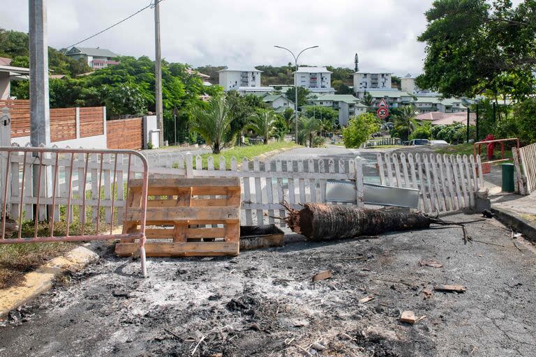 Una barricada instalada por los residentes para bloquear el acceso y canalizar a los activistas independentistas a la entrada de Tuband, en el distrito de Motor Pool de Noumea, el 15 de mayo de 2024, en medio de las protestas vinculadas a un debate sobre un proyecto de ley constitucional destinado a ampliar el electorado para las próximas elecciones del territorio francés de ultramar de Nueva Caledonia. Una persona murió, cientos más resultaron heridas, se saquearon tiendas y se incendiaron edificios públicos durante una segunda noche de disturbios en Nueva Caledonia, según informaron las autoridades el miércoles, en un momento en que se desbordaba la ira por las reformas constitucionales de París. (Foto de Delphine Mayeur / AFP)