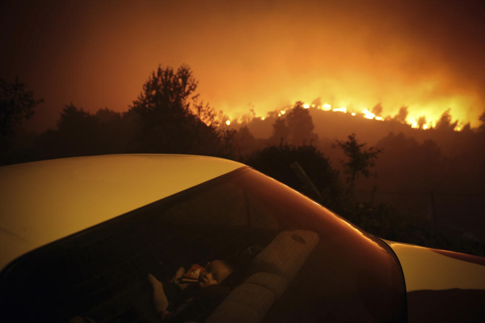 In this image released by World Press Photo, Thursday April 15, 2021, by Nuno Andre Ferreira, Agencia Lusa, titled Forest Fire, which won third prize in the Spot News Singles category, shows A child sits inside a car close by a forest fire in Oliveira de Frades, Portugal, on Sept. 7, 2020. (Nuno Andre Ferreira, Agencia Lusa, World Press Photo via AP)