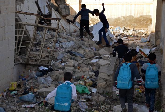 Iraqi children walk in rubble as they head to school in the battered city of Mosul on December 27, 2017 Through games, mime and sport, an instructor aims to help show the teachers -- some of whom are themselves traumatised -- how best to handle students struggling to cope with the mental scares of the Islamic State group rule and the fighting that ended it. (AFP Photo/Ahmad MUWAFAQ)