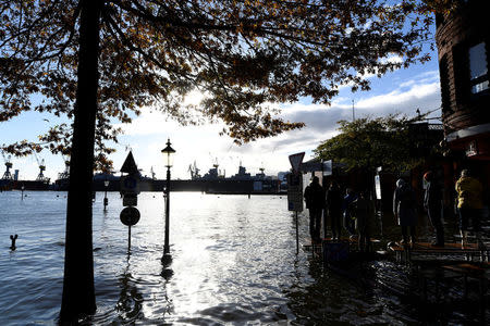 People take photos at the Fish Market flooded during stormy weather caused by a storm called "Herwart," in Hamburg, Germany October 29, 2017. REUTERS/Fabian Bimmer