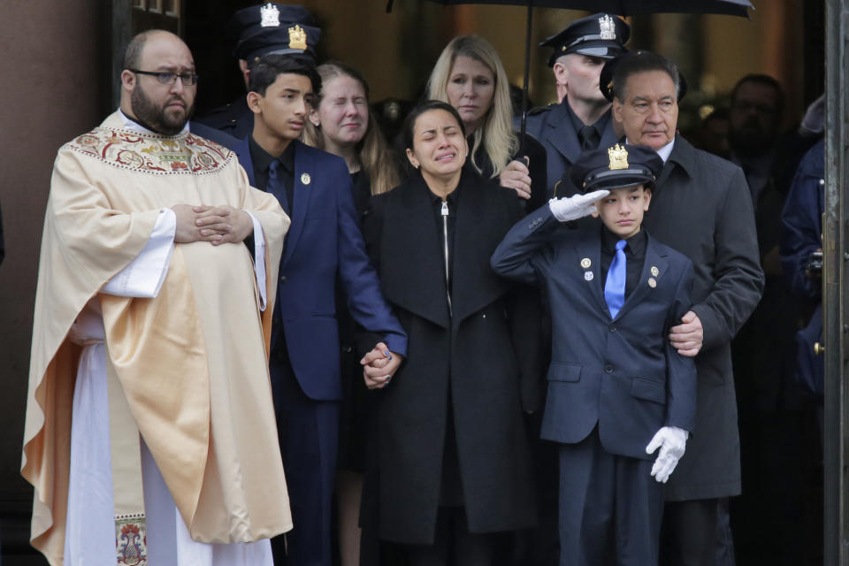 Mourners of Jersey City Police Detective Joseph Seals, including his wife Laura Seals, center, watch as his casket is carried out of the church in Jersey City, N.J., Tuesday, Dec. 17, 2019. The 40-year-old married father of five was killed in a confrontation a week ago with two attackers who then drove to a kosher market and killed three people inside before dying in a lengthy shootout with police. (AP Photo/Seth Wenig)