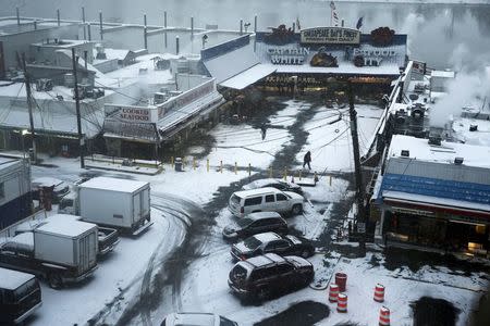 People buy seafood at the Wharf as the snow begins to fall in Washington January 22, 2016. REUTERS/Jonathan Ernst