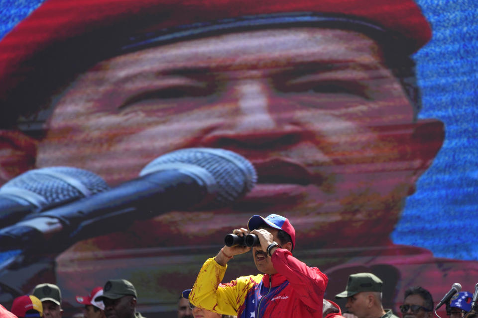 FILE - Venezuelan President Nicolas Maduro looks through a pair of binoculars while standing on the main stage during a commemorative event, in Caracas, Venezuela, Feb. 29, 2024. Maduro became Venezuela's interim president in March 2013 after the death of Hugo Chávez and elected a few months later. He is seeking his third six-year term in the upcoming presidential election. (AP Photo/Ariana Cubillos, File)