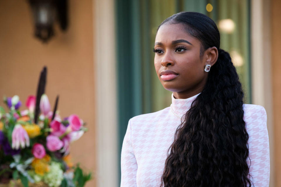 Coco Jones as Hilary Banks staring out into a crowd while rocking a side ponytail