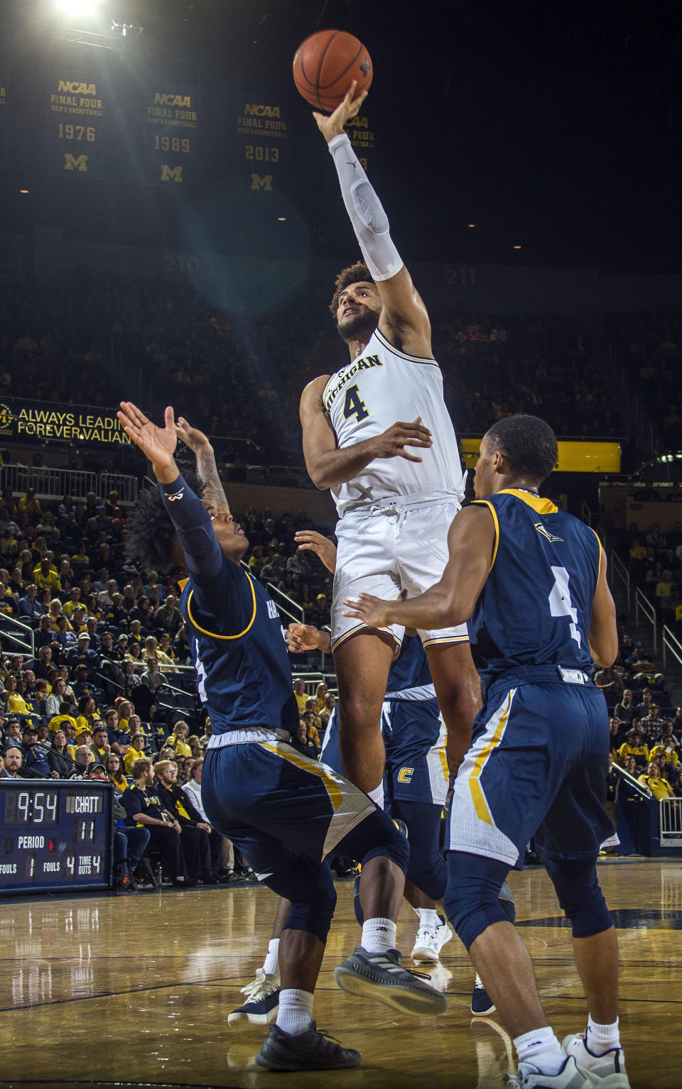 Michigan forward Isaiah Livers (4) attempts to shoot while defended by Chattanooga guards Donovann Toatley, left, and Maurice Commander, right, in the first half of an NCAA college basketball game at Crisler Center in Ann Arbor, Mich., Friday, Nov. 23, 2018. (AP Photo/Tony Ding)