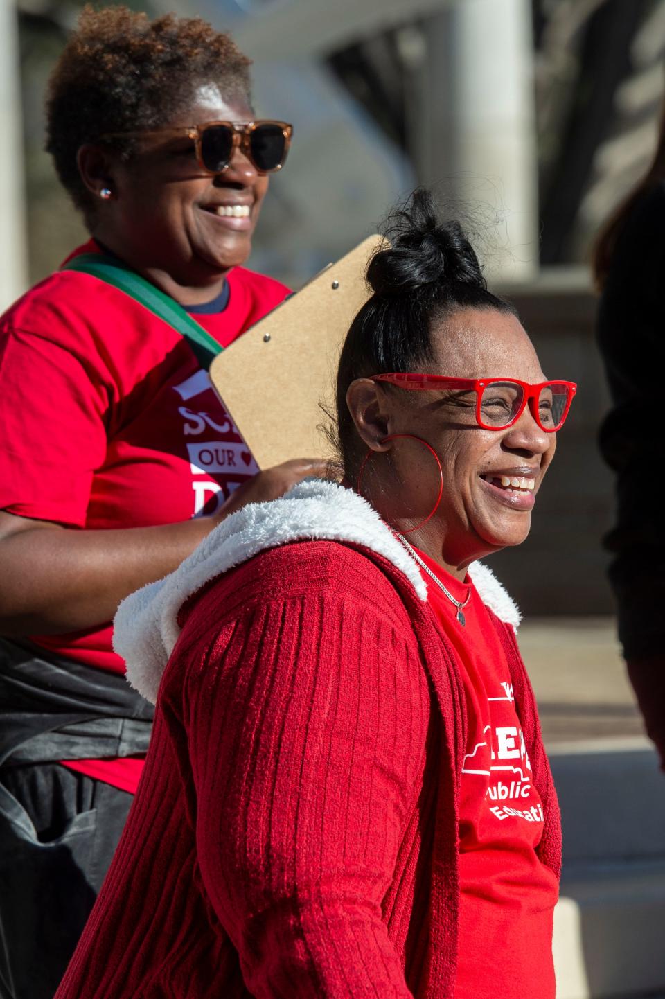 Latonya Best, front, and Cassandra Wells smile as they participate in a chant during a teachers rally at Pack Square Park March 20, 2023.