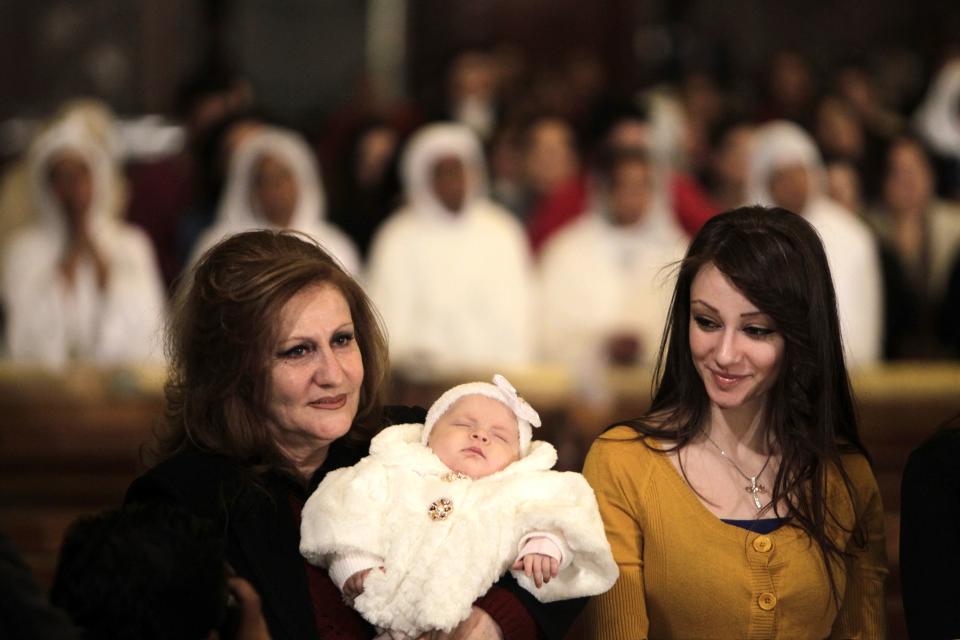 A Coptic Egyptian woman carries a baby during a Coptic Christmas eve mass in Cairo