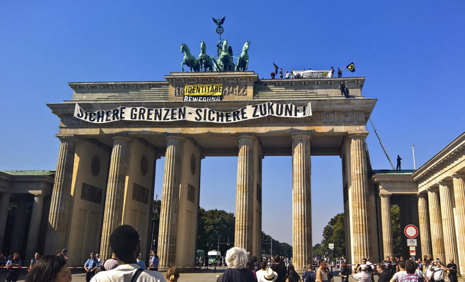 FILE - In this Aug. 27, 2016 file photo, activists of the Identitarian Movement protest on the Brandenburg Gate in Berlin, Germany, with a banner reading 'secure borders - secure future'. The German domestic intelligence agency says it is stepping up observation of the far-right Identitarian Movement in Germany that campaigns against immigrants and Islam. (AP Photo/Frank Jordans)
