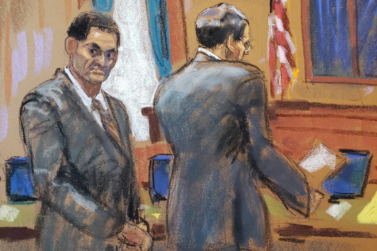 A courtroom sketch of Sam Bankman-Fried standing next to and looking behind his lawyer.