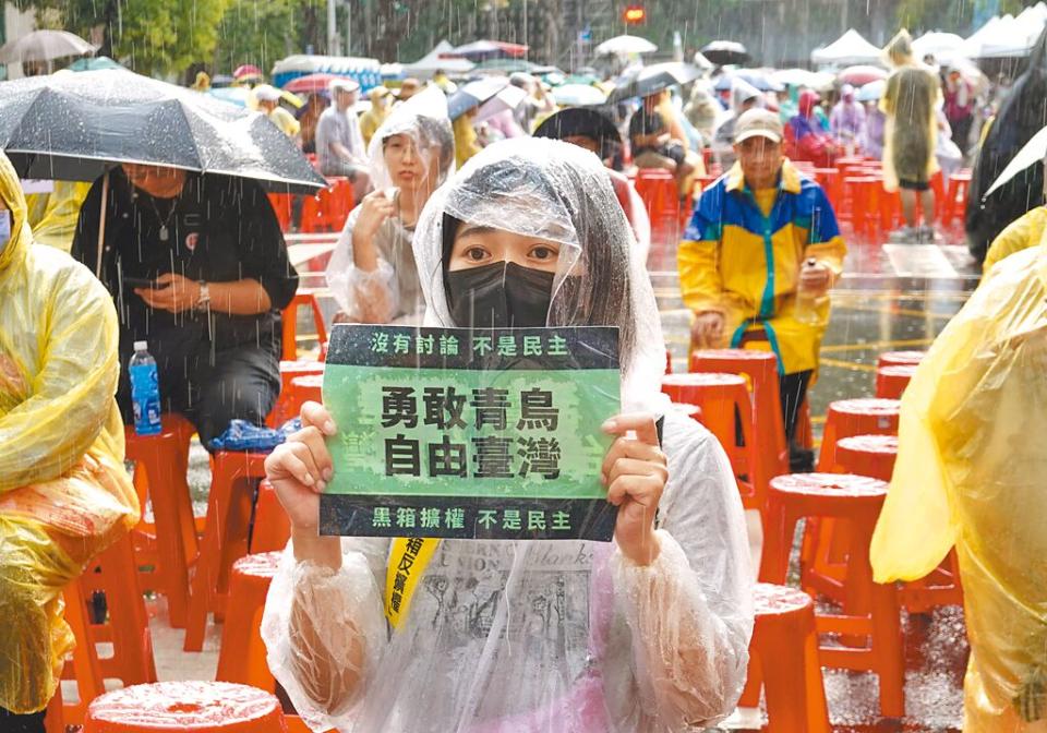 參與「青鳥行動」的民眾淋著雨，手持標語抗議立法院黑箱擴權。（姚志平攝）
