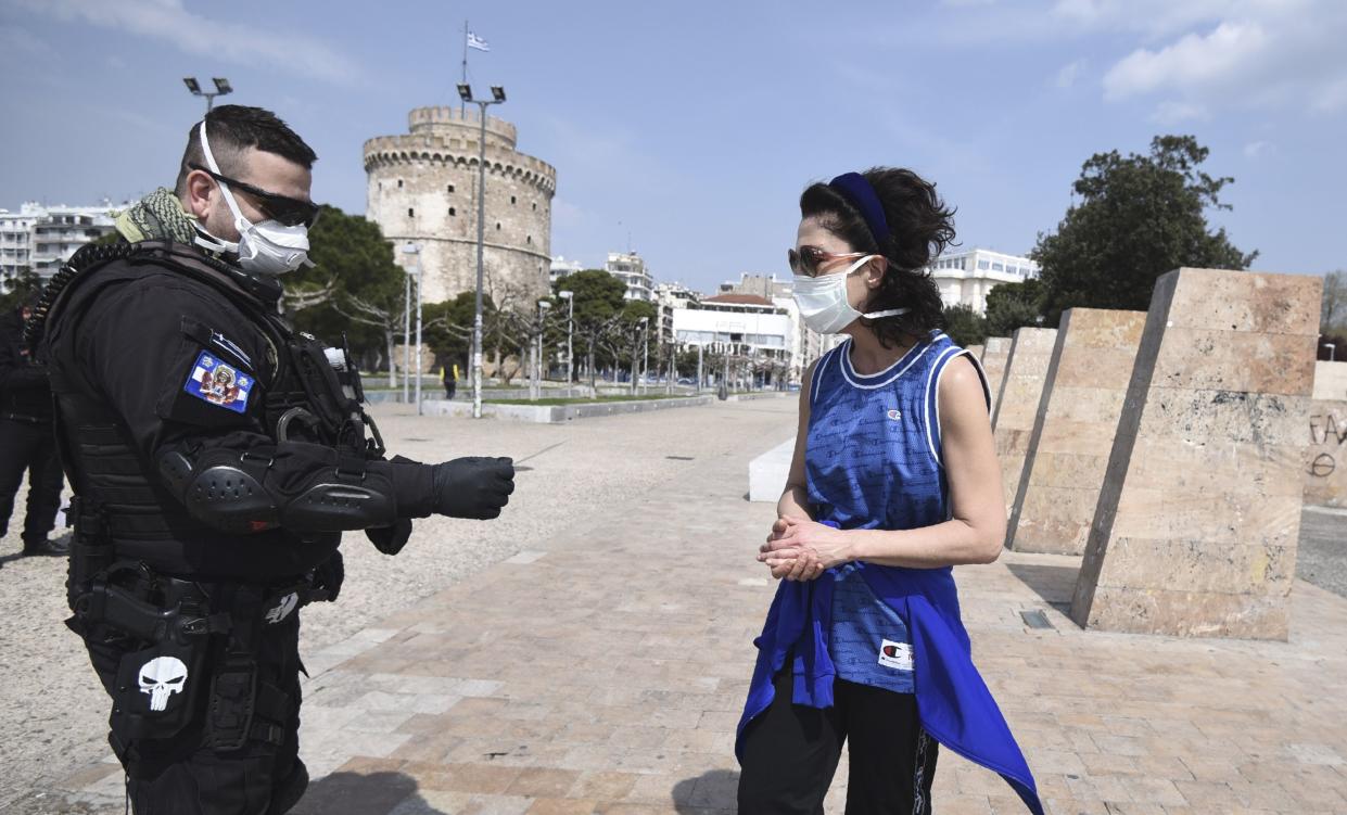 A policeman check a runner for valid documents during a lockdown order by the Greek government to control the spread of the new coronavirus in the northern city of Thessaloniki, Greece, Tuesday, March 31, 2020. Greek authorities are banning access to a popular pedestrian waterfront area in Thessaloniki, after good weather saw people congregating despite the country's lockdown measures to prevent the spread the COVID-19.