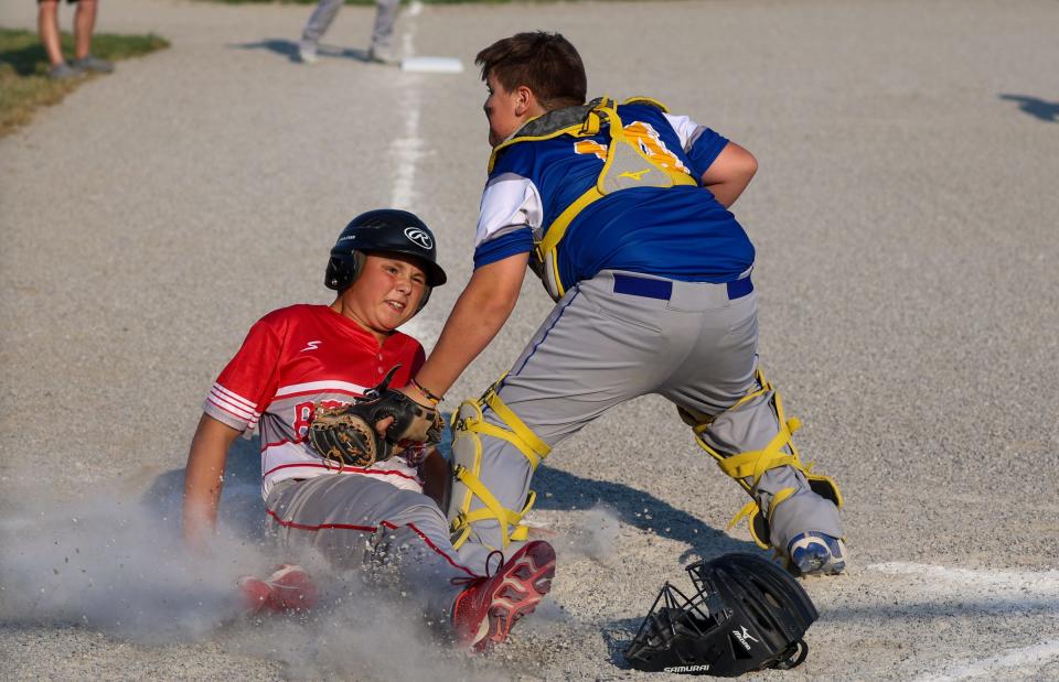 Peyton Clawson of Bedford Elite slides under a tag by Ida catcher Kade Uhl in the finals of the 63rd annual Monroe County Fair Baseball Tournament Wednesday. Ida won the title with a 7-5 win.