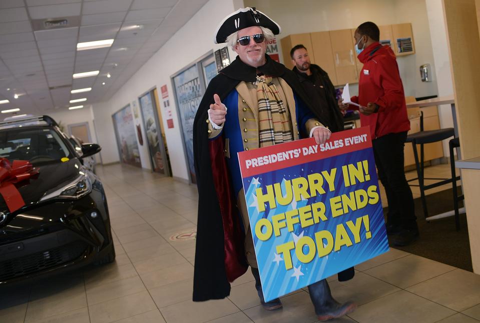 A man dresses like George Washington during Presidents Day in 2022 in an effort to bring in customers to a Toyota dealer in Massechusetts. Many businesses offer sales and deals on the federal holiday.