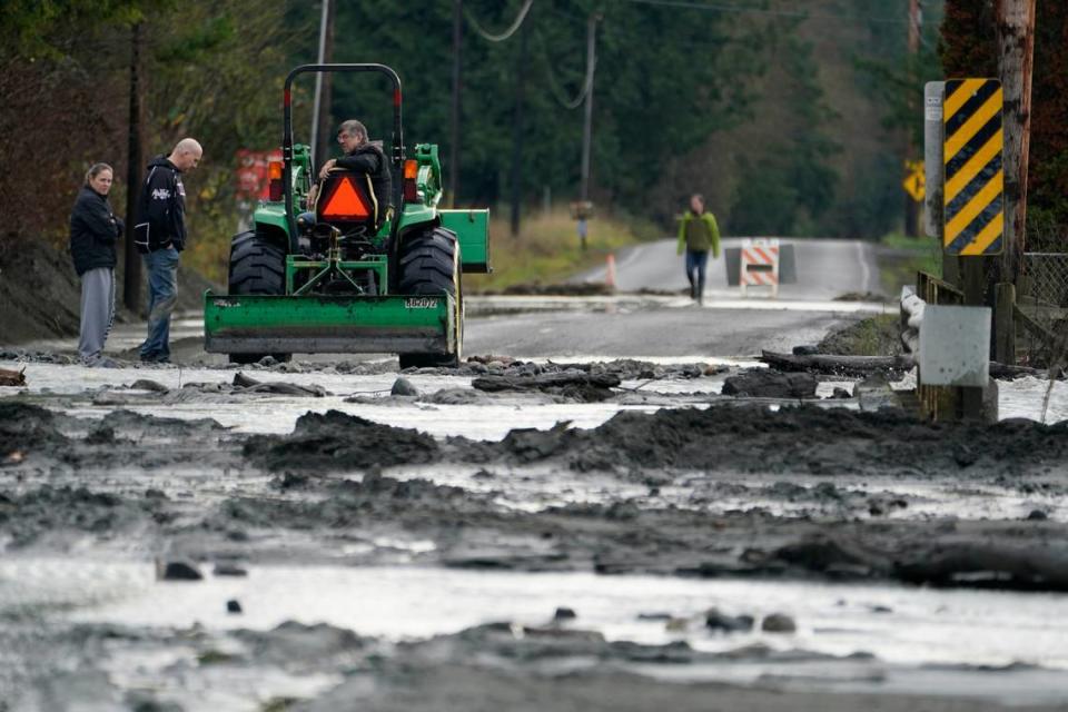 A tractor operator talks with people standing near a mud- and debris-covered road near Everson Monday, Nov. 29.