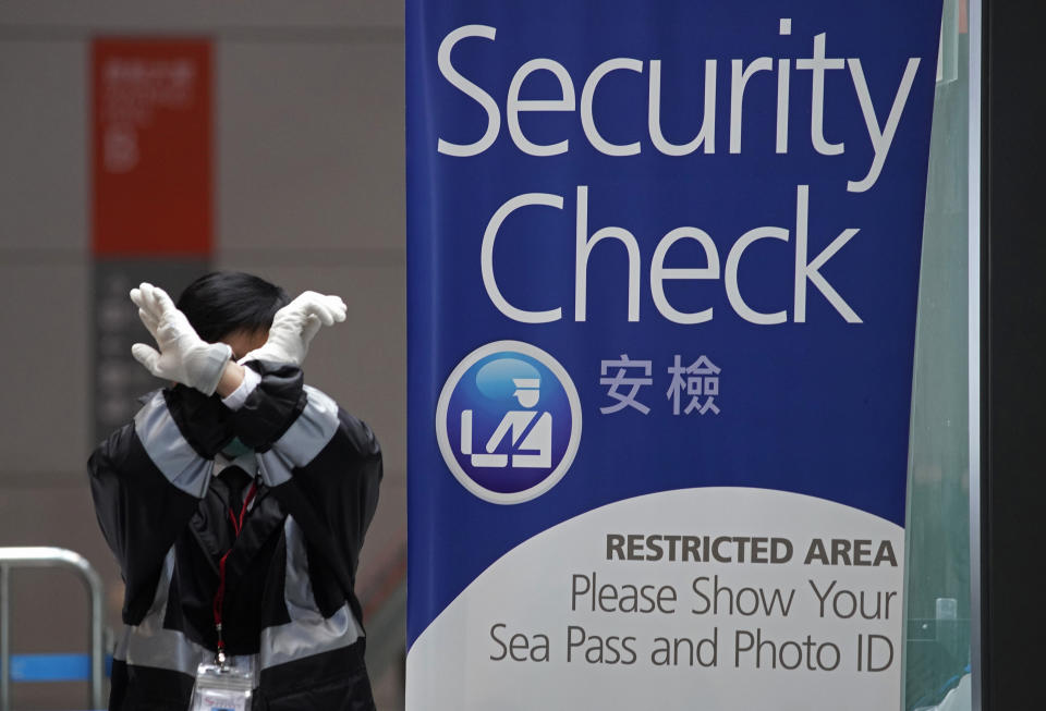 A security guard gestures at the Kai Tak Cruise Terminal in Hong Kong, Wednesday, Feb. 5, 2020. A Hong Kong official says more than 1,800 people on board a cruise ship that was turned away from a Taiwanese port will be quarantined until they are checked for a new virus. (AP Photo/Vincent Yu)